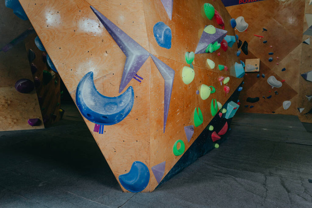 Mur moderne de gymnase d'escalade intérieure avec variété de poignées de maintien pour les mains et les pieds. Activités sportives. - Photo, image