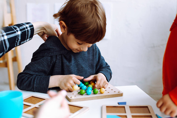 Kaunis pieni poika taitto värikkäitä yksityiskohtia rakentaja pöydällä leikkihuoneessa lähikuva. Mielenkiintoinen peli päiväkodeissa kehittää logiikkaa ja älykkyyttä. Viestintä lasten kanssa päiväkodissa. - Valokuva, kuva