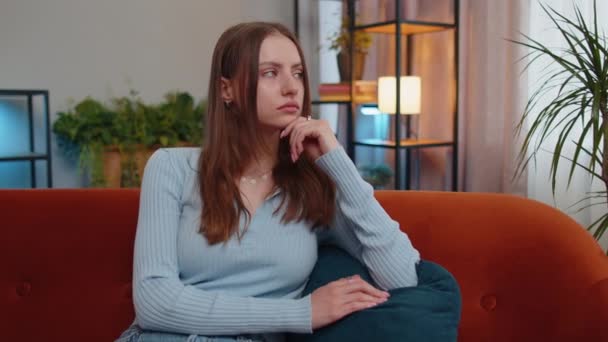 Portrait of sad young woman sitting at home looks pensive thinks over life concerns or unrequited love, suffers from unfair situation. Problem, break up, depressed girl feeling bad annoyed, burnout - Filmagem, Vídeo