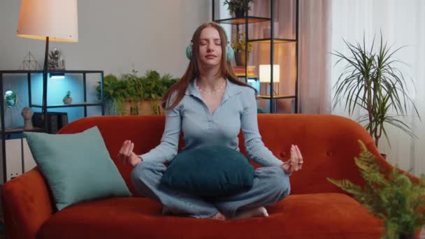 Sakin ol, rahatla, iç denge. Genç kadın derin nefes alıyor Mudra jesti ile, gözleri kapalı meditasyon yapıyor konsantre düşüncelerle, huzurlu zihinle. Yorgun kız, oturma odasında kanepede oturur. - Video, Çekim