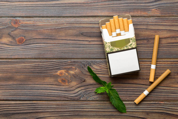 Pack of menthol cigarettes and fresh mint on colored table, Menthol cigarettes top view flat lay. - Photo, Image