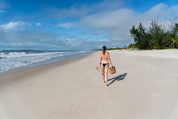 Donna in bikini che cammina sulla sabbia della spiaggia contro il cielo blu. Valenca, Bahia, Brasile. - Foto, immagini