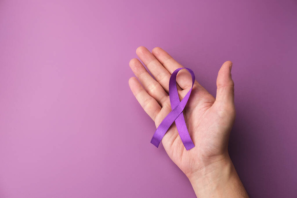 Фиолетовая лента как символ Всемирного дня борьбы с раком на фиолетовом фоне, пространство для копирования. - Фото, изображение