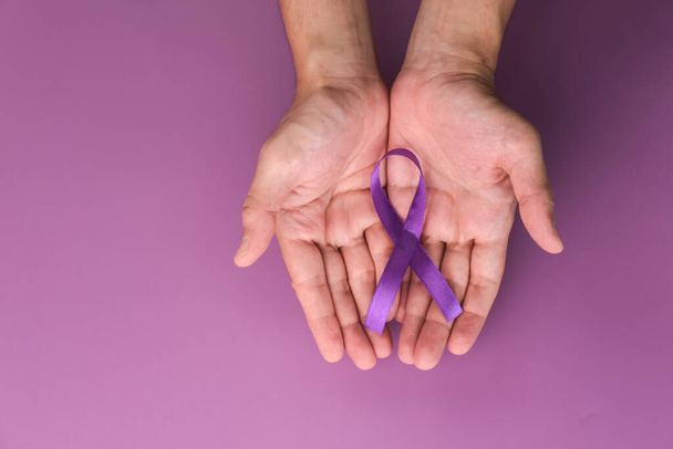 Purple ribbon as symbol of World Cancer Day over purple color background, copy space. - Φωτογραφία, εικόνα