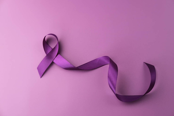 Fioletowa wstążka jako symbol Światowego Dnia Raka na fioletowym tle koloru, przestrzeń kopiowania. - Zdjęcie, obraz
