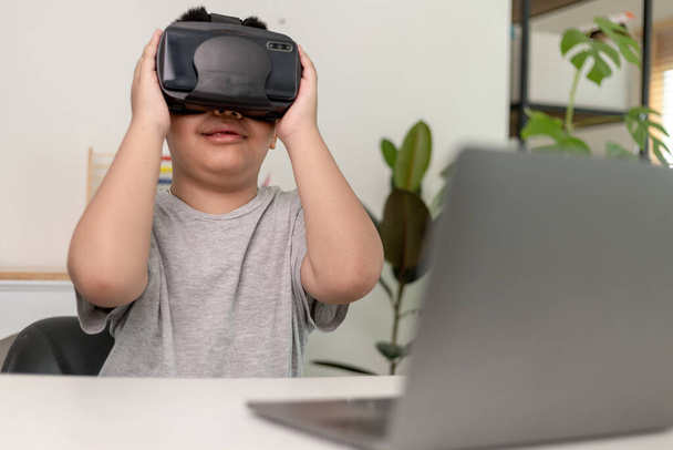 Asiatique Petit garçon avec des lunettes VR étudier les sciences à la maison, étudiant curieux porte un casque de réalité virtuelle pour étudier la science à la maison étude en ligne apprentissage du mode de vie futuriste - Photo, image