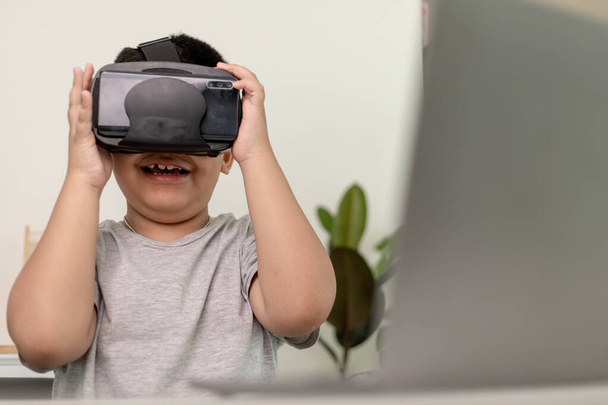 Asiatique Petit garçon avec des lunettes VR étudier les sciences à la maison, étudiant curieux porte un casque de réalité virtuelle pour étudier la science à la maison étude en ligne apprentissage du mode de vie futuriste - Photo, image