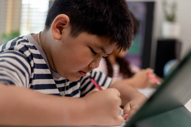 Азійські хлопчики і дівчатка люблять навчатися в Інтернеті, роблячи нотатки і використовуючи вдома таблички.. - Фото, зображення