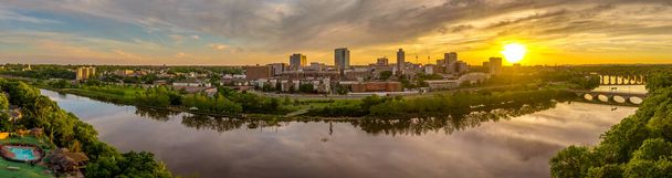 Vista aérea del centro de Nuevo Brunswick y la Universidad de Rutgers mientras el sol se pone detrás de los edificios de gran altura y reflexionar sobre el río Raritan - Foto, Imagen