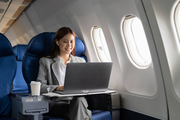 Крупним планом бізнес азіатська жінка використовує ноутбук під час польоту на літаку біля вікна
 - Фото, зображення