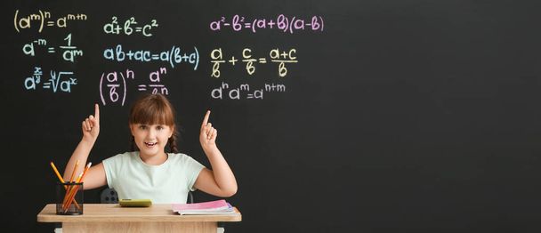 Cute uczennica siedzi na biurku podczas lekcji matematyki w klasie - Zdjęcie, obraz