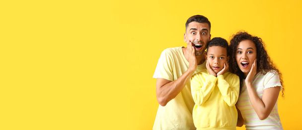 Familia interracial sorprendida sobre fondo amarillo con espacio para texto - Foto, imagen