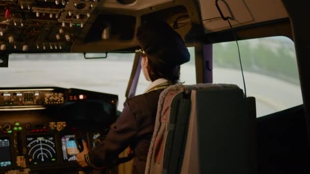 Portret van vrouwelijke copiloot vliegend vliegtuig met gezagvoerder in cockpit, gebruikmakend van bedieningspaneel navigatie op power dashboard. Voorruit van het luchtvaartuig om te vliegen met motorcommando. Handschot. - Video