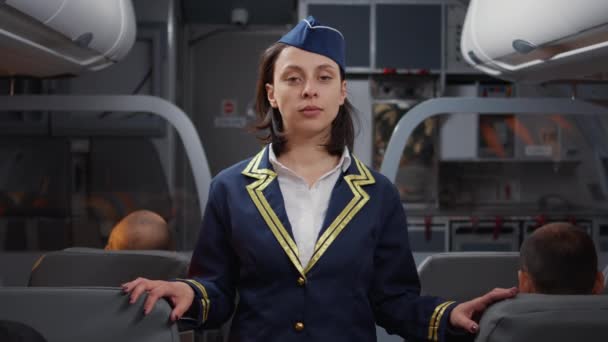Portret van een vrouwelijke stewardess in luchtvaartuniform die mensen instapt in het vliegtuig, helpt met stoelen. Zittend in het gangpad om passagiers te begroeten op vliegtuig jet, internationale luchtvaartmaatschappij dienst. - Video