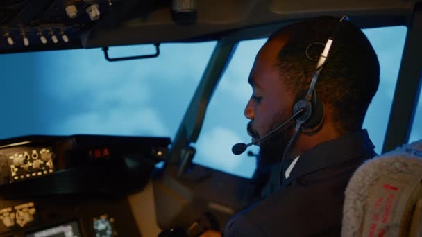 Afro-Amerikaanse copiloot die gebruik maakt van vliegtuigcommando 's om vliegtuig te vliegen, stuwkrachtmotor om op te stijgen. Bedieningspaneel navigatie met radar kompas en dashboard in kapitein cabine. Een handschot. Sluiten.. - Video