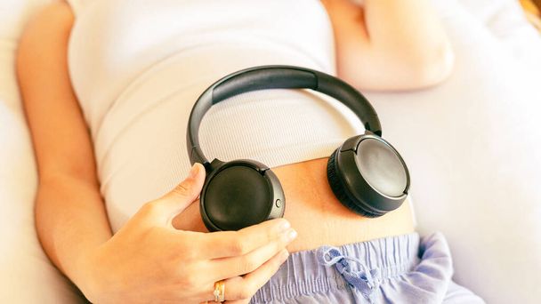 Pregnancy music woman listen. Pregnant woman listening to music. Mother belly listen headphones sound. Concept of pregnancy, maternity, expectation for baby birth - Фото, изображение