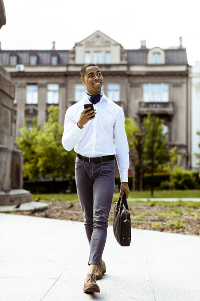 Юний афроамериканський бізнесмен, який користується мобільним телефоном на вулиці. - Фото, зображення