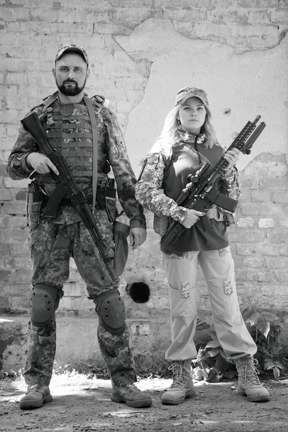 Hombre y mujer, defensores ucranianos con armas cerca del edificio destruido durante la guerra en Ucrania - Foto, Imagen