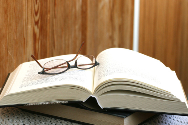 dickes aufgeschlagenes Buch und darauf eine Brille - Foto, Bild
