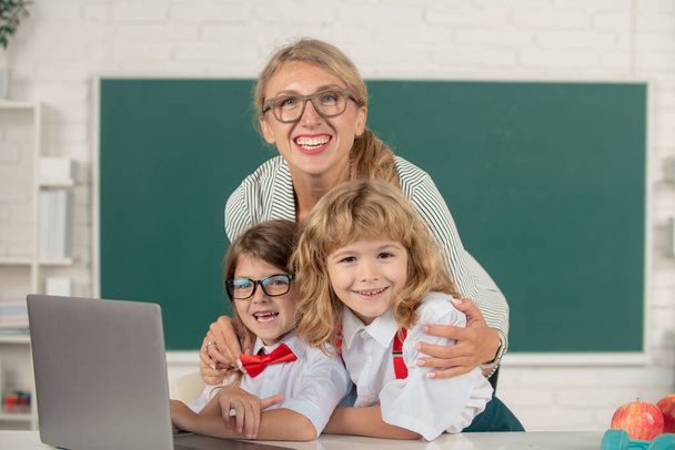 First day at school. Cute little boy from elementary school and tutor teacher studying lesson on laptop in class. School education and children concept - Foto, immagini