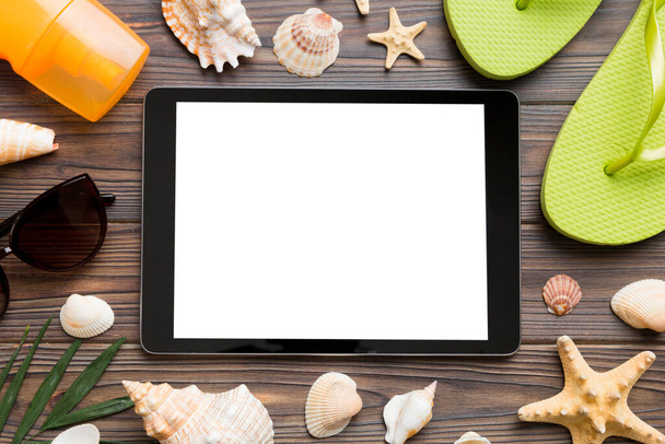 Composición plana con tableta y accesorios de playa sobre fondo de color. Tablet ordenador con pantalla en blanco maqueta con espacio de copia. - Foto, imagen