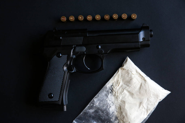 弾丸がテーブルの上に横たわっている銃。犯罪問題だ。薬と黒の背景。違法販売. - 写真・画像