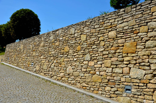 beautifully folded retaining wall with a granite attic with small joints. brown beige yellow irregular gneiss stone holding a slope above it. there are undemanding perennials around - Photo, Image