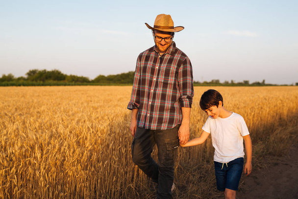 father and son walking through wheat field - Valokuva, kuva