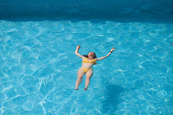 πάνω όψη της γυναίκας που επιπλέει στην πισίνα - Φωτογραφία, εικόνα