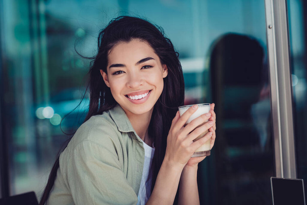 Photo of cheerful pretty lady dressed casual clothes sitting cafeteria enjoying cappuccino outside urban town house. - Fotoğraf, Görsel