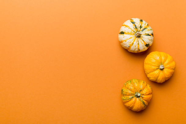 Осенняя композиция маленьких оранжевых тыкв на фоне цветного стола. Осень, Хэллоуин и День благодарения. Осенняя квартира лежала фотография. Вид сверху в пространстве для копирования. - Фото, изображение