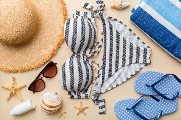Woman swimwear and beach accessories flat lay top view on colored background Summer travel concept. bikini swimsuit, straw hat and seasheels. Copy space Top view. - Foto, immagini
