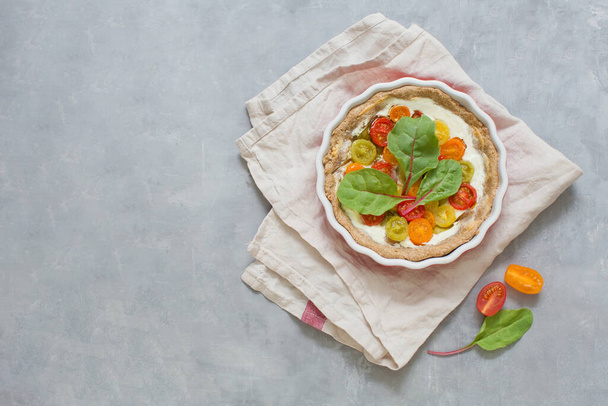 Crostata vegetale al forno con foglie di insalata d'oro in teglia su fondo grigio cemento. Torta con pomodori, concetto di cibo con spazio copia - Foto, immagini