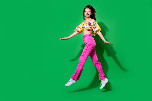 Full length photo of adorable shiny lady wear off shoulders blouse jumping walking empty space isolated green color background. - Foto, Imagem