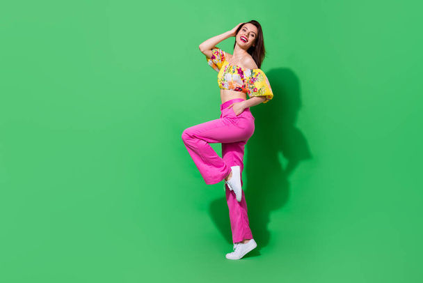 Full body profile photo of elegant cheerful young lady stand tiptoe have good mood isolated on green color background. - 写真・画像