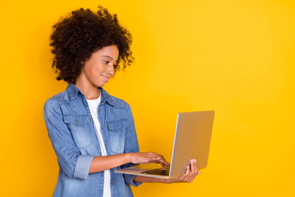 Portrait of attractive cheery skilled teen girl using laptop writing e-mail isolated over shine yellow color background. - Fotó, kép