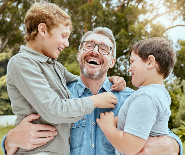 Een gelukkige blanke alleenstaande ouder die geniet van het spelen met zijn zonen in de achtertuin. Glimlachende familie van drie mannetjes die alleen plezier hebben in een tuin buiten. - Foto, afbeelding
