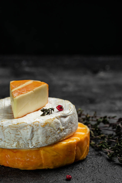 Set of Camembert, Brie, Gorgonzola blue cream cheese with basil leaves and cherry tomatoes on a dark background. vertical image. top view. place for text. - 写真・画像