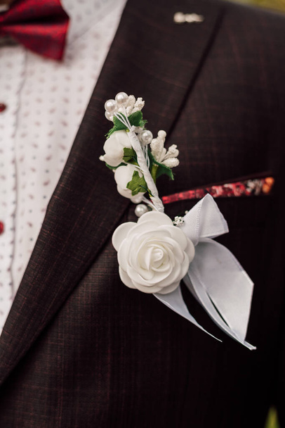 Der Bräutigam trägt ein weißes Hemd und hält den Brautstrauß in der Hand. Makroschießen. Details zur Hochzeit - Foto, Bild