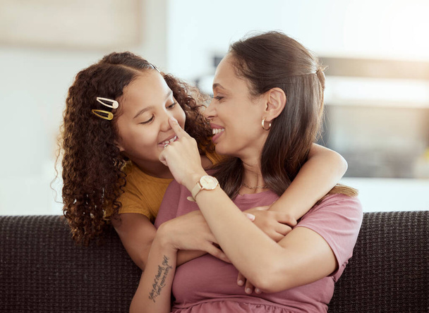 Gemischte Rasse alleinerziehende Mutter und Tochter, die sich im heimischen Wohnzimmer umarmen. Lächelndes hispanisches Mädchen, das sich in der Lounge mit einem alleinerziehenden Elternteil umarmt und verbindet. Glückliche, liebevolle Frau und Kind am Wochenende zusammen. - Foto, Bild