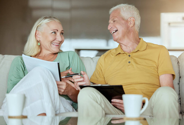 Счастливая пожилая пара проверяет свои финансы и планирует пенсию. Старший кавказский мужчина и женщина улыбаются, планируя и делая бумажную работу дома. - Фото, изображение