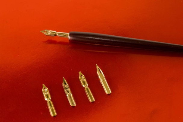 Photo picture of an antique ink fountain pen and nibs on red background - 写真・画像