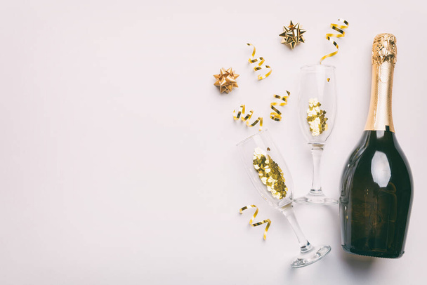 bottle of champagne with glasses and colorful confetti on colored background. top view flay lay. - Foto, Imagem