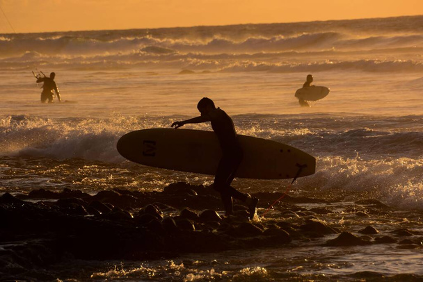 surfistas surfeando las olas al atardecer - Foto, Imagen