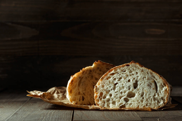 Bread, traditional sourdough bread cut into slices on a rustic wooden background. Concept of traditional leavened bread baking methods. Healthy food. - Zdjęcie, obraz