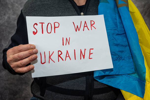 az ember keze egy posztert tart a szöveggel Állítsa meg a háborút Ukrajnában. Oroszország mint teoretikus teljes elszigeteltsége - Fotó, kép