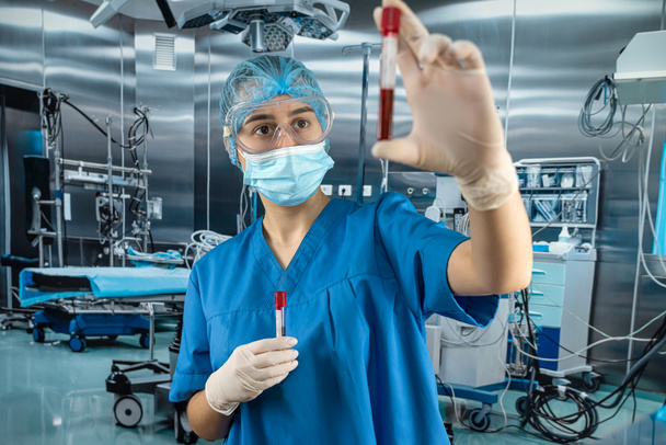 νοσοκόμος στο νοσοκομείο που κρατάει αίμα σε δοκιμαστικούς σωλήνες για ανάλυση. Εργασίες σε κλινικό εργαστήριο - Φωτογραφία, εικόνα
