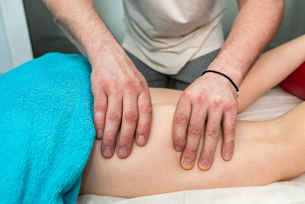 Masseur making relax massage procedure in leg female client in spa salon. Beauty treatment concept - Фото, зображення