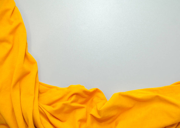 Κίτρινο τσαλακωμένο ύφασμα σε γκρι φόντο. - Φωτογραφία, εικόνα