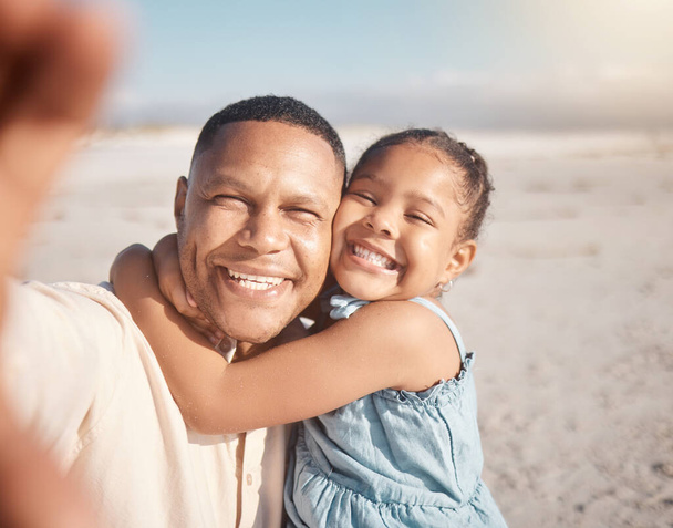 Smiling mixed race single father taking selfie with little affectionate daughter on beach. Adorable, happy, hispanic girl bonding and hugging parent. Man and child enjoying free time together outside. - Photo, Image